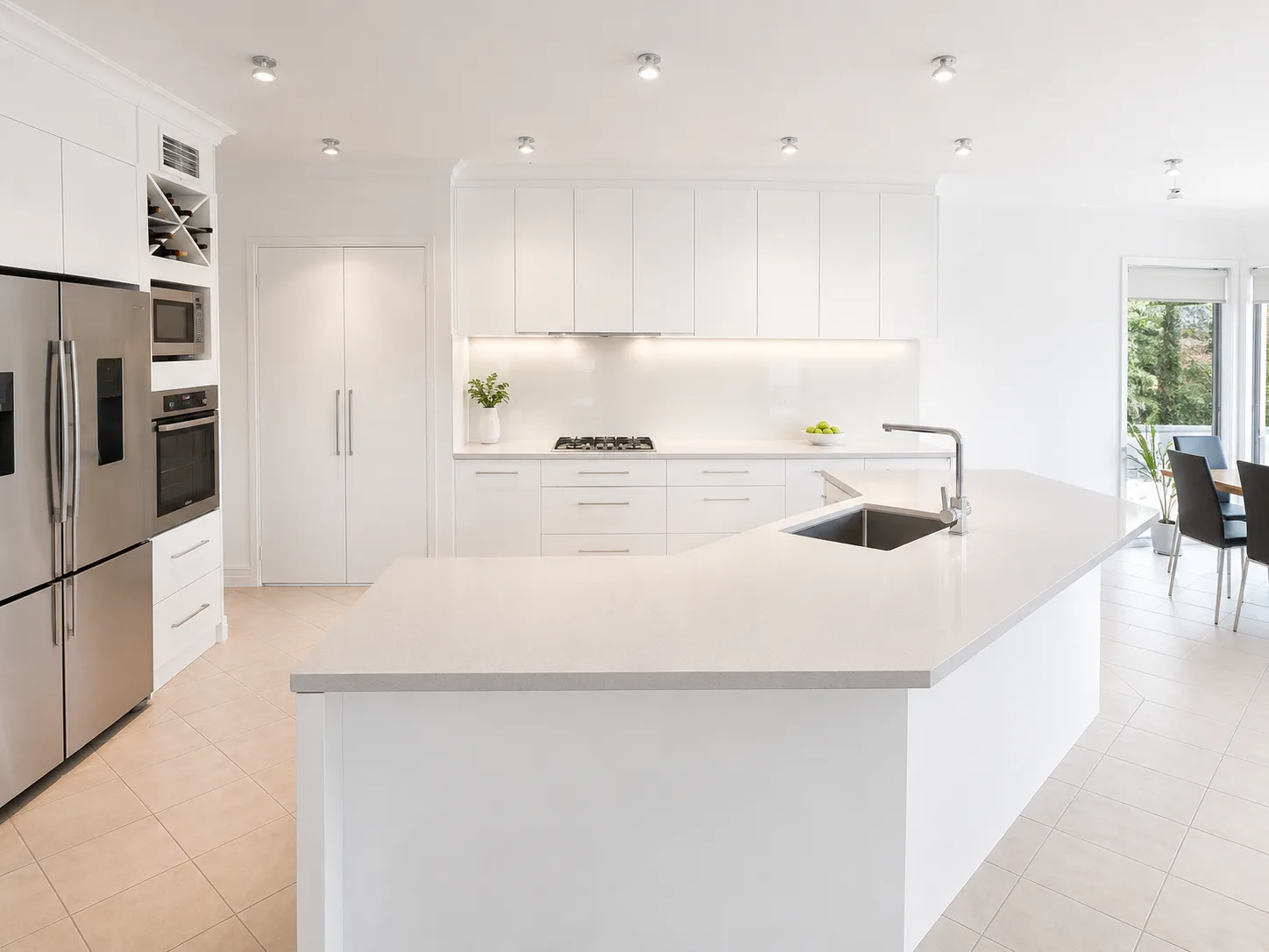 Bright white kitchen with large island bench and integrated appliances