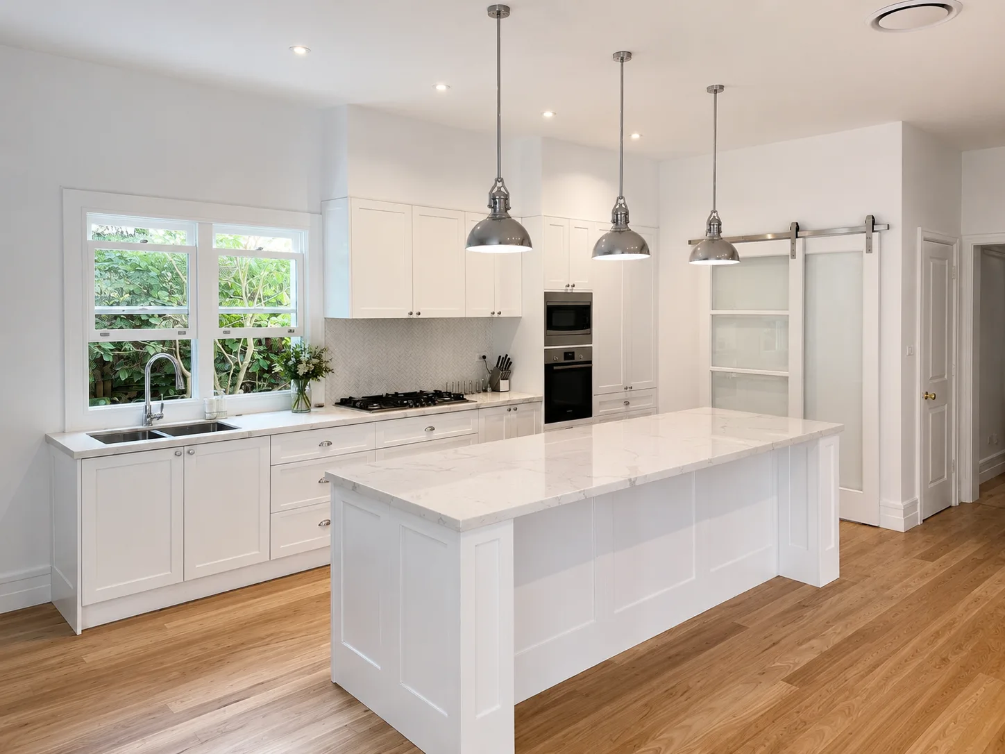 Bright white Hamptons-style kitchen with island bench and pendant lighting