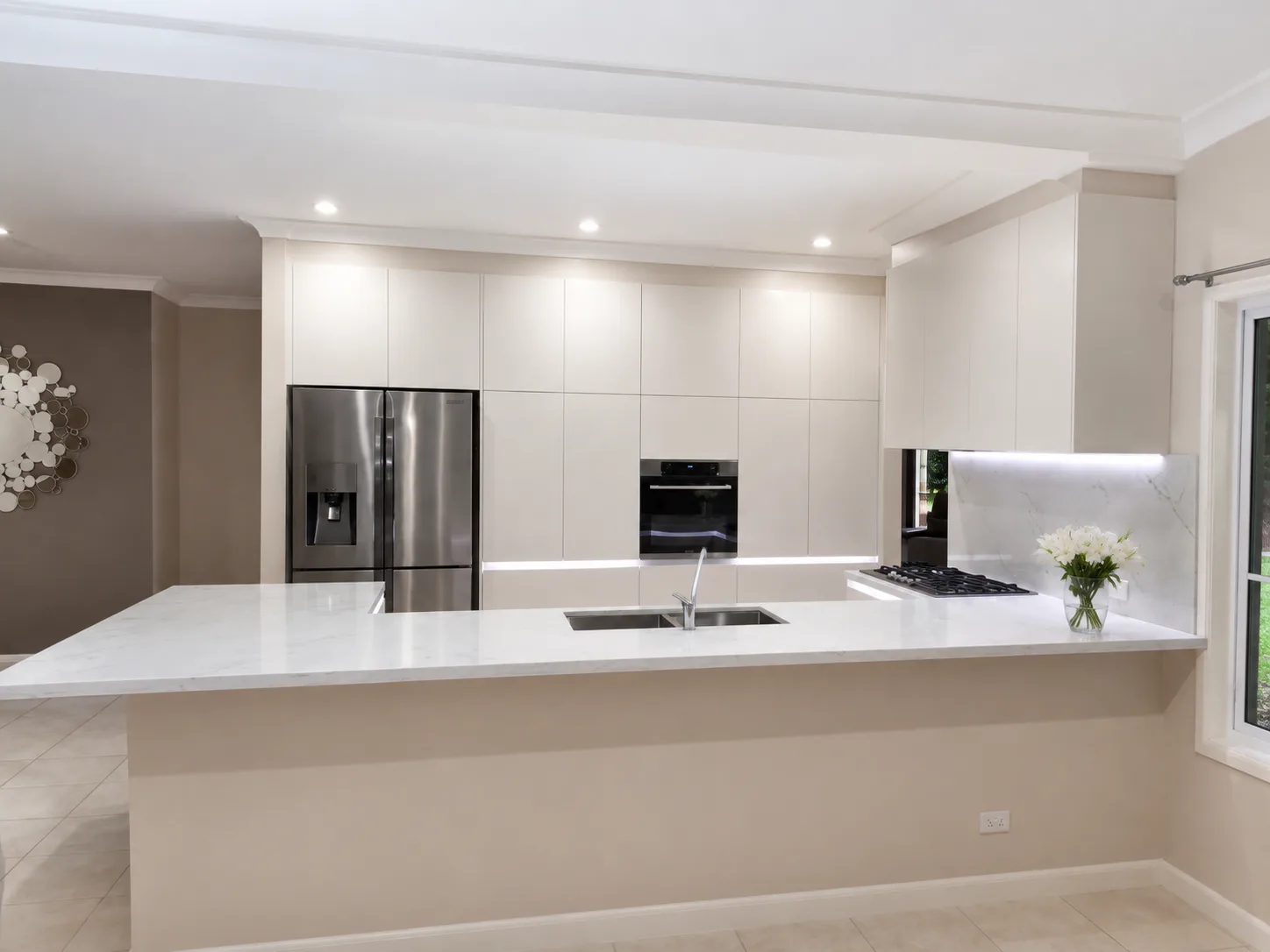 Integrated kitchen cabinetry with marble-look benchtop and under-cabinet lighting